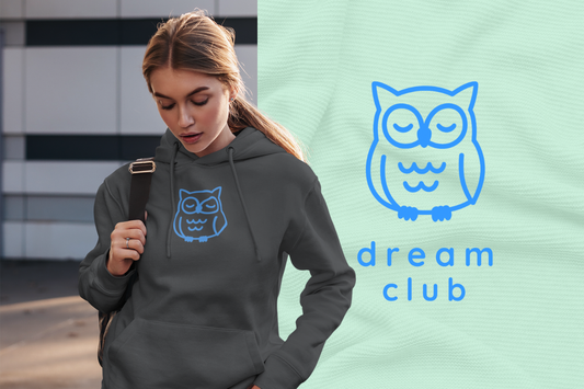 Woman wearing Owl Hoodie, standing next to dream club logo and text.